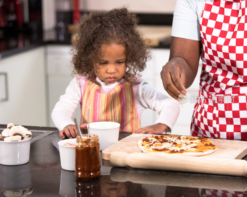 父母/照顾者和混血小女孩一起做披萨